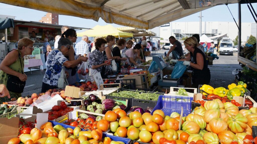 Banco di verdura fresca e interazione tra venditore e cliente in un mercato rionale